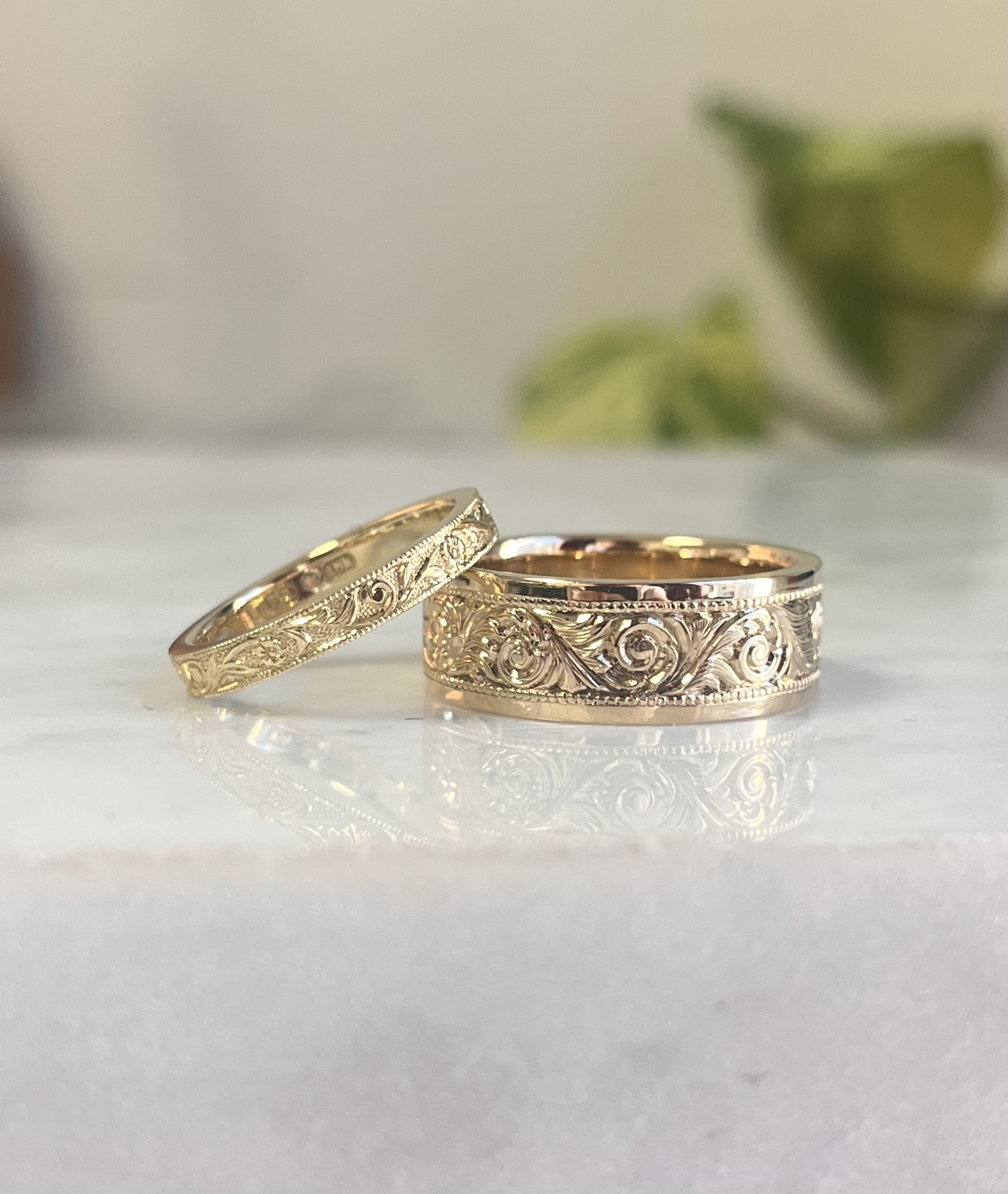 Pair of hand-engraved yellow gold wedding bands showing ornate scrollwork detail