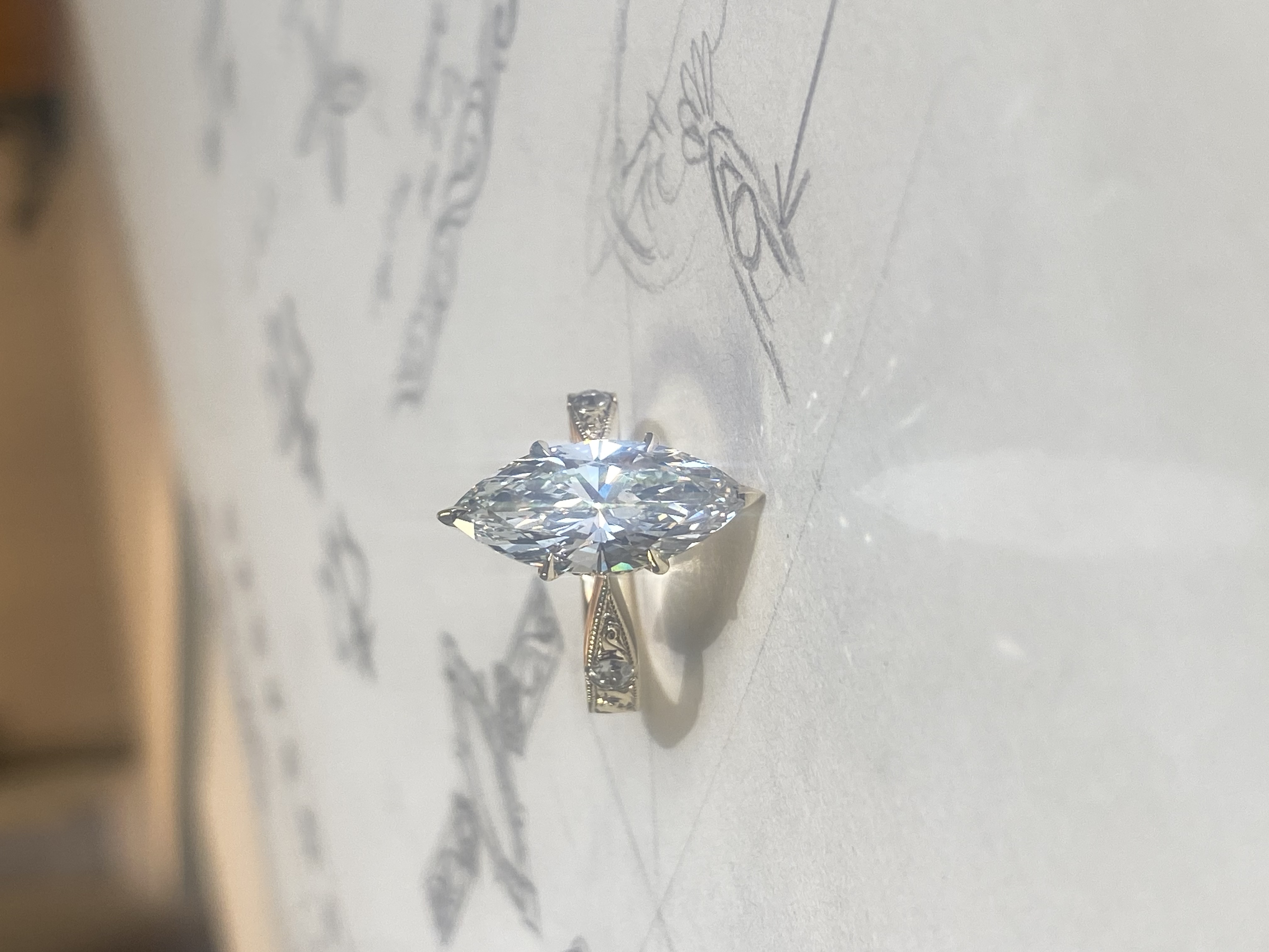 Marquise diamond engagement ring resting on original design sketches by Alex Bär — Bear Goldsmithing Toronto