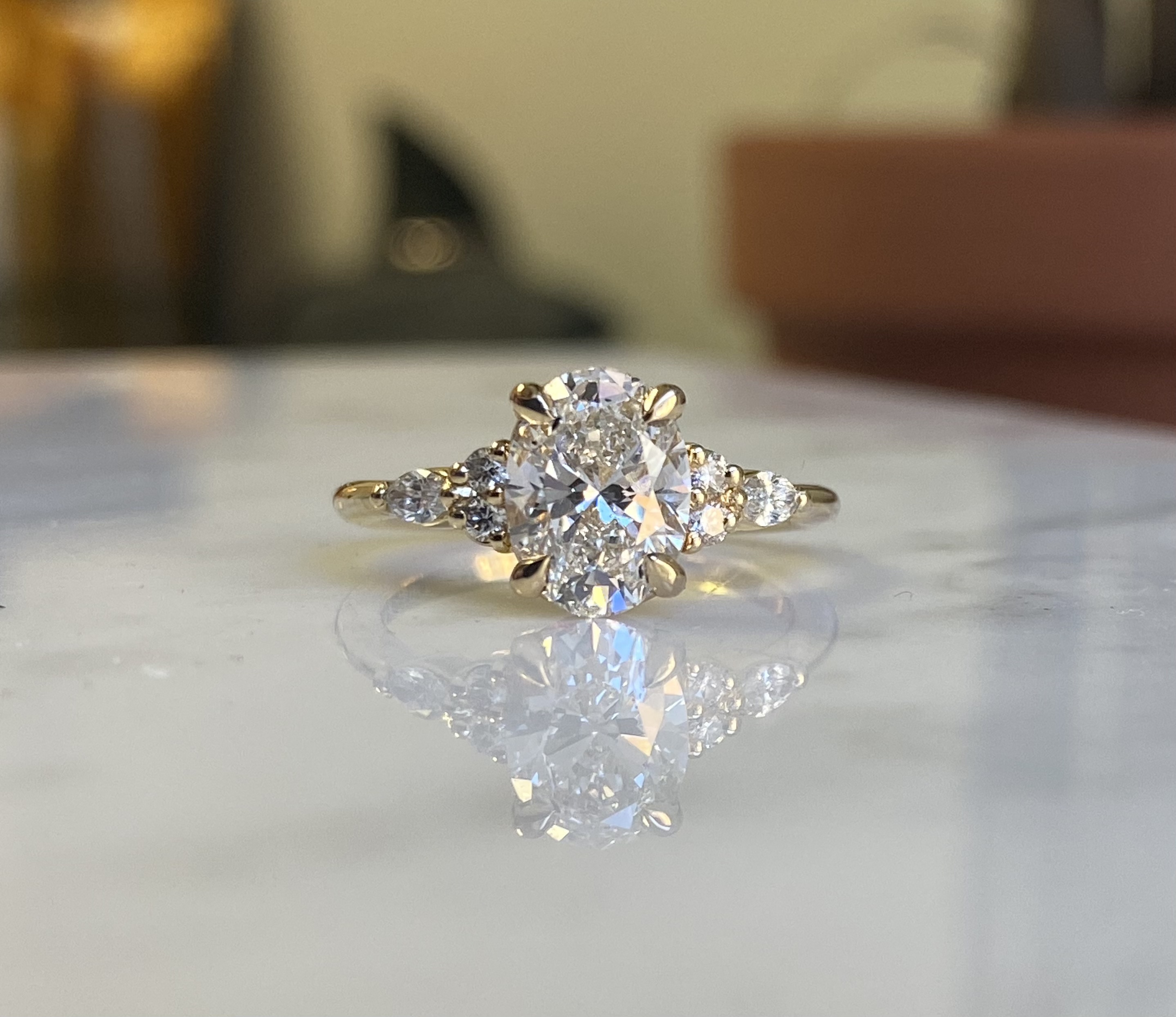 Oval diamond with pear and round cluster sides — custom engagement ring Toronto