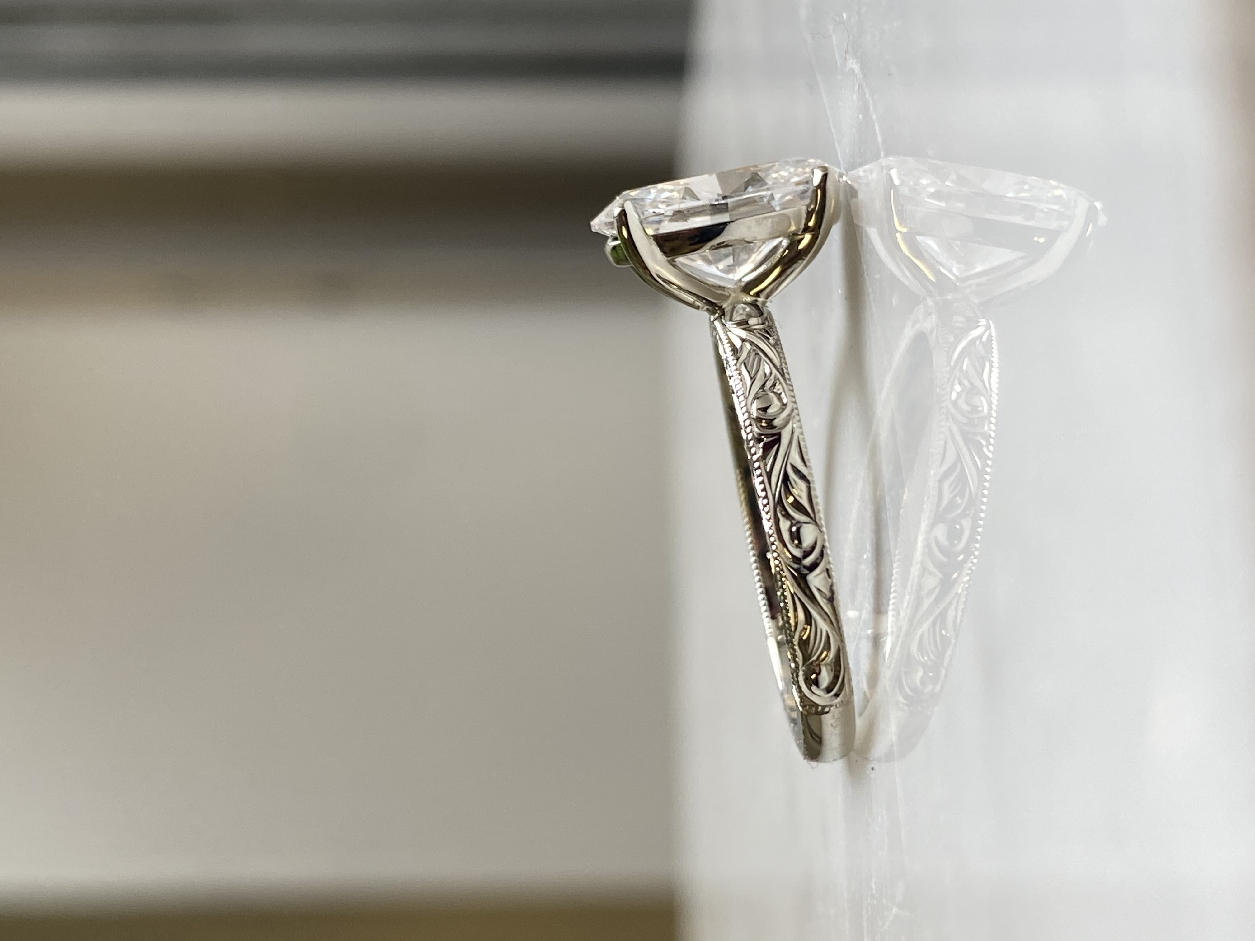 Oval diamond solitaire white gold rounded shank side profile showing full scrollwork engraving and milgrain edge — Bear Goldsmithing Toronto